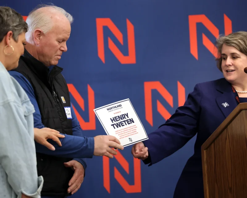 Sandy Kiddoo, President Northland Community and Technical College, presents Tim and Coleen Tweten a card to replicate a plaque that will be placed near apple trees in the courtyard at the East Grand Forks college in honor of Tim's father, Henry Tweten, a longtime champion and advocate of the school during a 50th anniversary celebration Friday, April 28, 2023 at Northland.