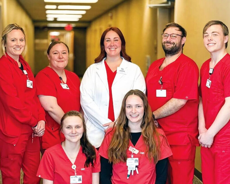 Front row (seated): Hailee Harris and Savannah Dennis. Back row (standing): Chelsey Veer, Kristen Wiese, Laura Dvergsten, David Boser and Will Tofstad pose at a healthcare facility connected to Northland Community & Technical College’s nursing program partnership with LifeCare.